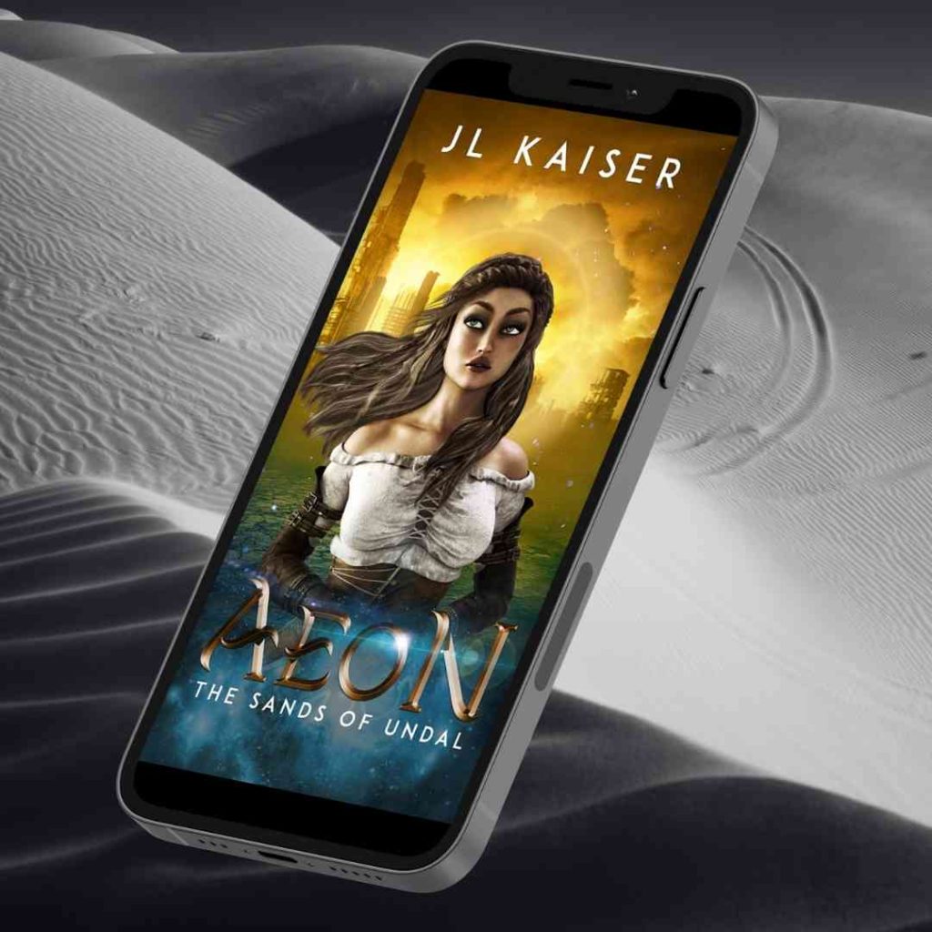 Floating over a background of sand dunes, a cellphone displays the cover of JL Kaiser's AEON The Sands of Undal. In it, a girl's torso is prominent, over gold clouds.
