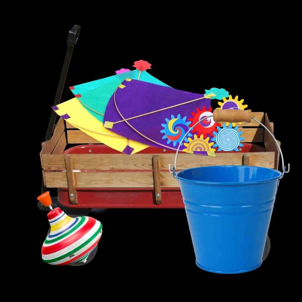 This picture shows a red metal wagon with wooden sides. A spinning top and a blue bucket sit next to it, and inside it is a set of toy gears and a few kites.