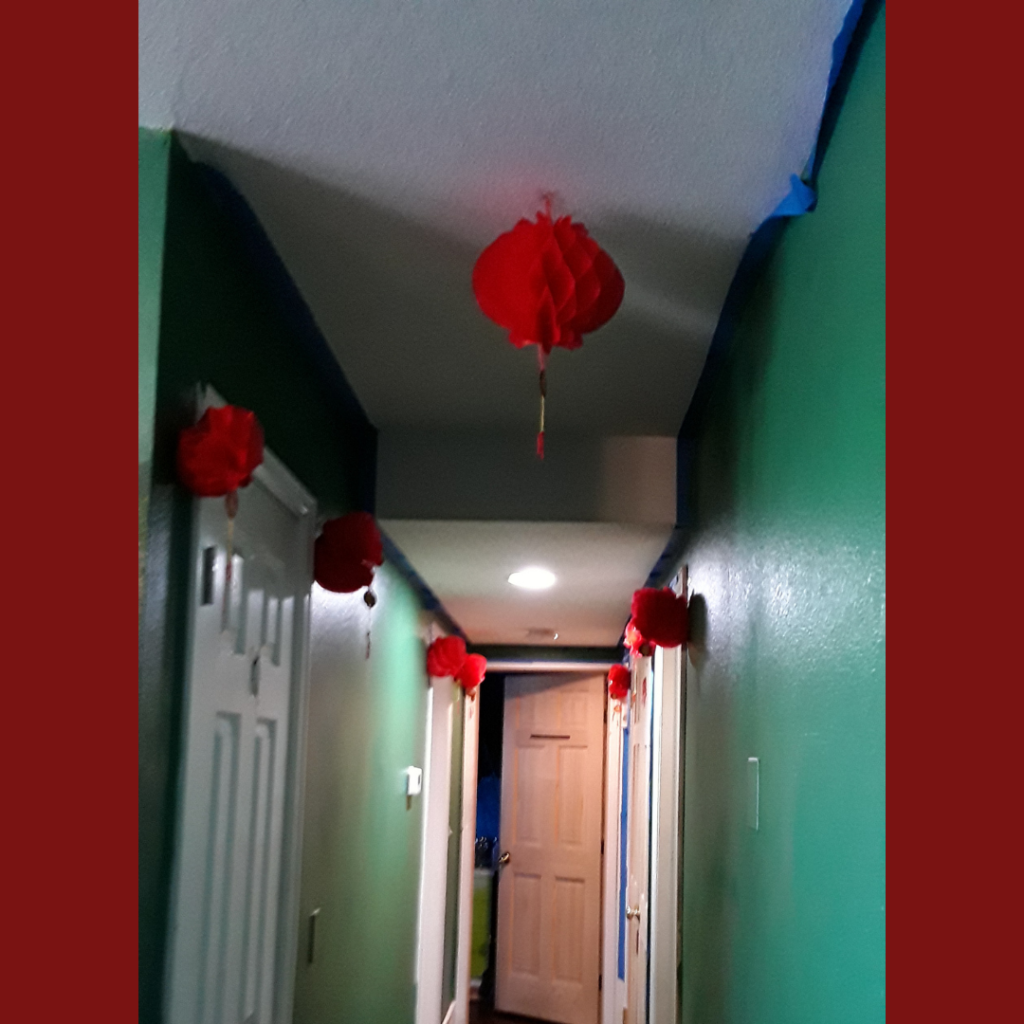 red paper lanterns hang near doorways in a hallway, hung for the holidays
