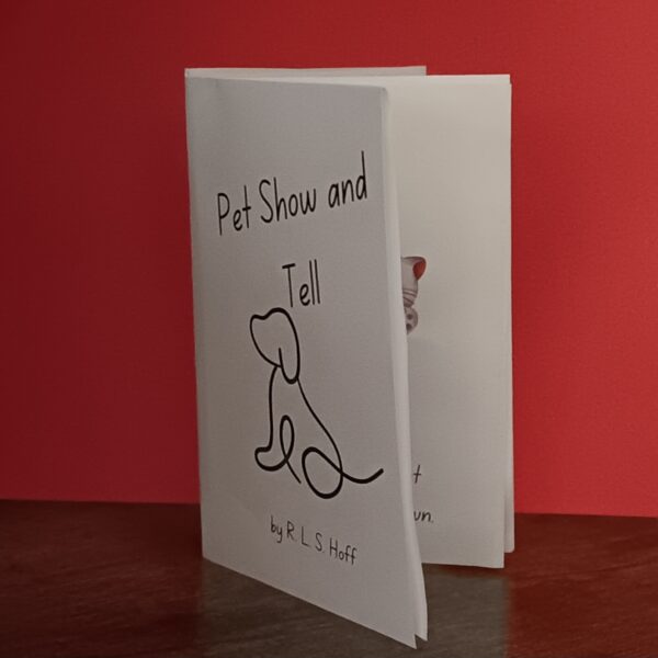 A Pet Show and Tell Zine sits on a wooden table in front of a red background.